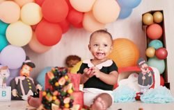 baby in white and black dress sitting on white and blue textile